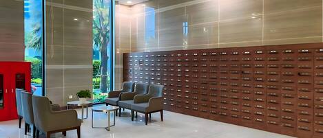 A modern lobby with a seating area, a wall of lockers, and a large window with a view of greenery.