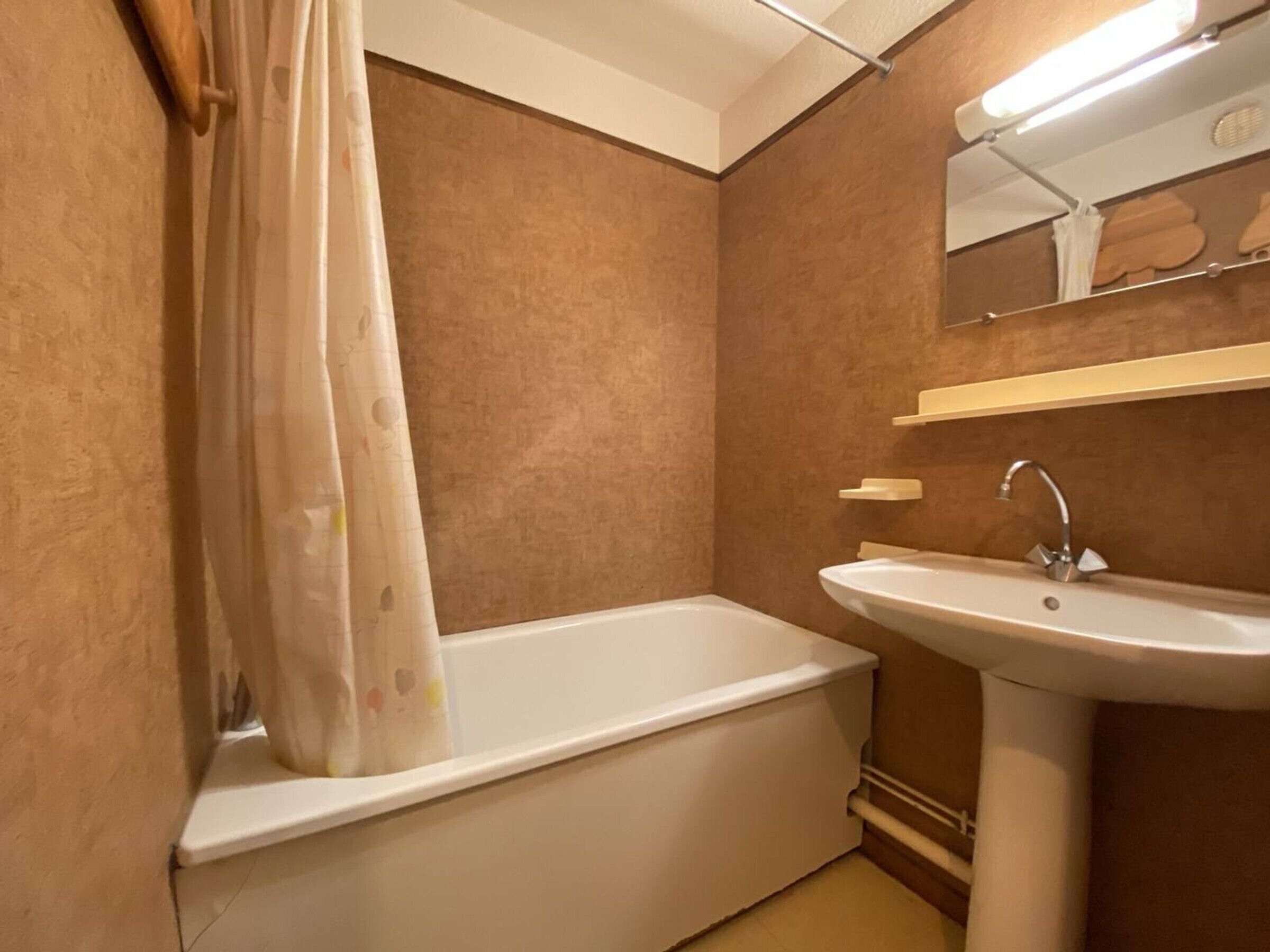 A bathroom with a bathtub, a sink, and a mirror.