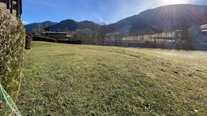A grassy field with a building and mountains in the background.