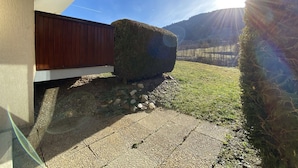 A house with a stone patio, a wooden fence, and a hay bale.