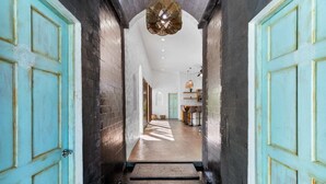 A hallway with turquoise doors, a wooden staircase, and a modern interior with a dining area. - Modern Home with Chic Bohemian Style and “Zen” Outdoor Oasis with Swimming Pool and Tiki-Style Dining Space (Potrero)