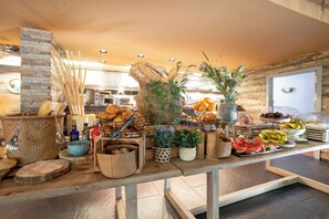 Una mesa de buffet con pan, frutas y varios recipientes.