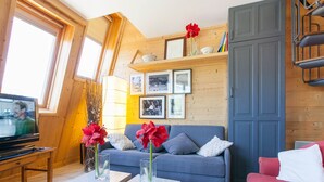Ein gemütliches Wohnzimmer mit einem blauen Sofa, einem roten Sitzsofa und einem Fernseher auf einem Holztisch.
