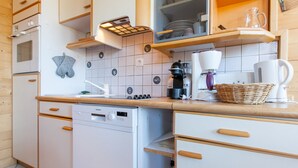 Eine kleine Küche mit Geschirrspüler, Backofen und Kaffeemaschine.