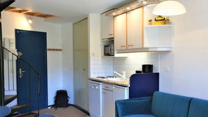A compact kitchen with white cabinets, a microwave, and a coffee maker. There's a blue sofa and a dining table with chairs. - Sunny duplex for 6 in Avoriaz (Avoriaz)