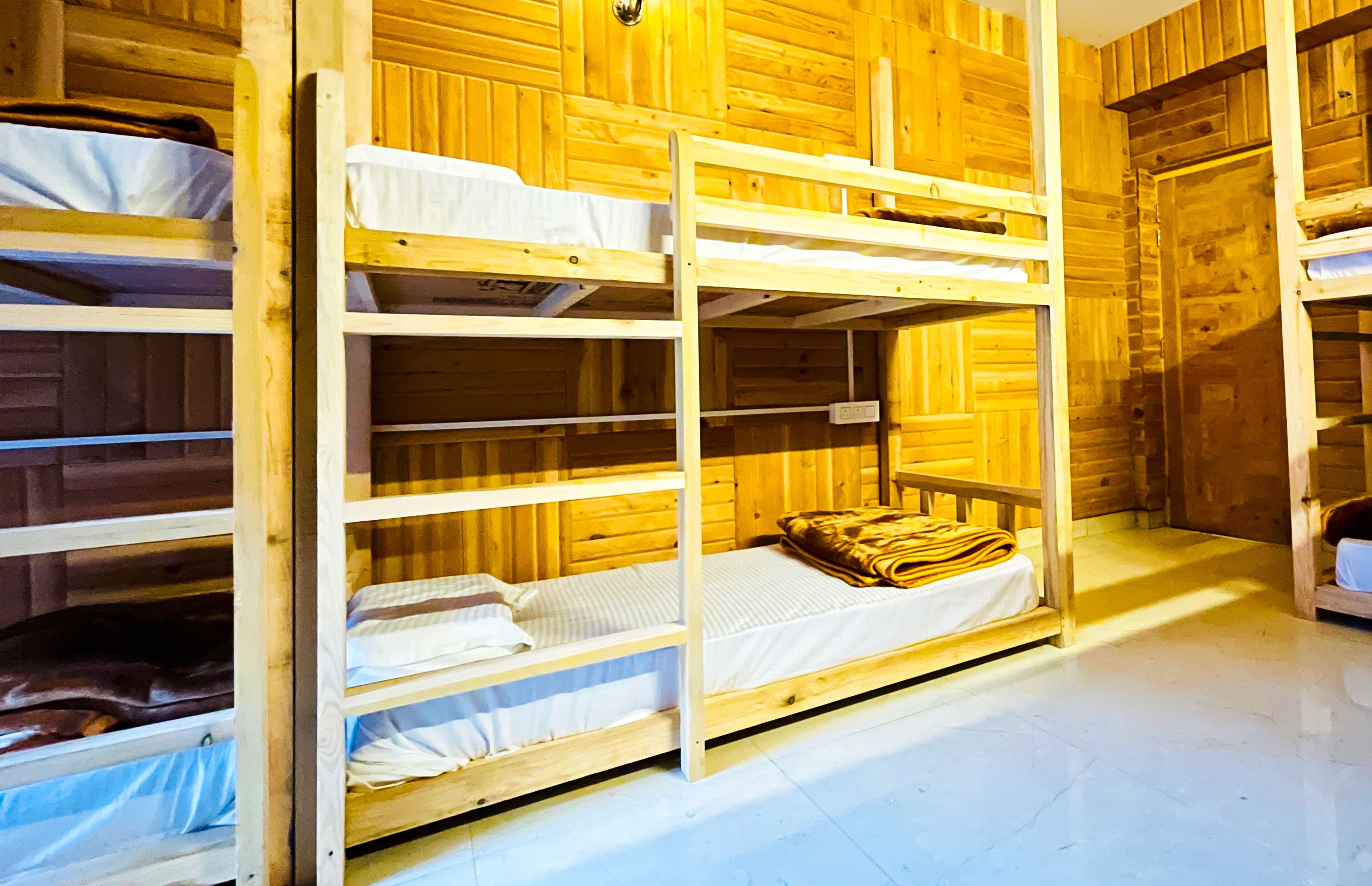 Une chambre avec des lits superposés, des murs en bois et un plancher blanc.