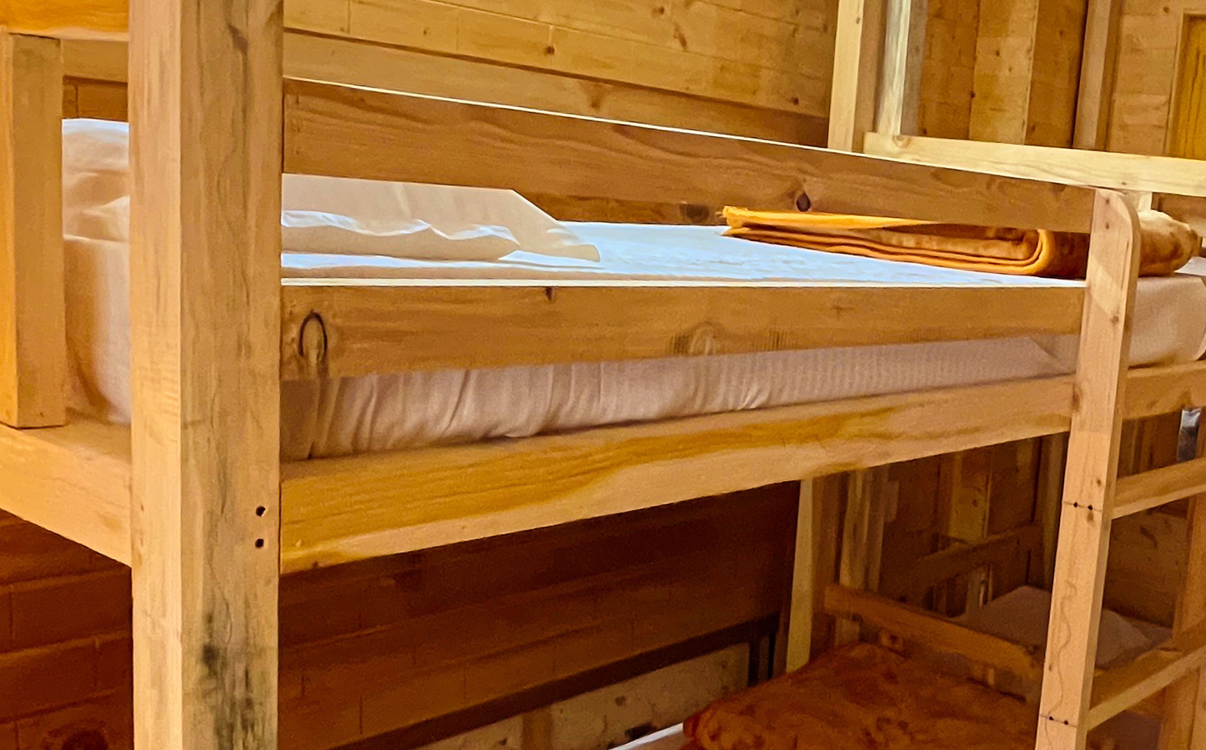 A wooden bunk bed with a mattress and pillows.