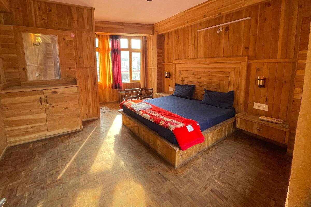 Et hyggeligt, træhytte-lignende værelse med en seng, et lille bord og en stol.