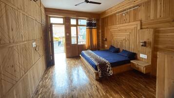 A wooden room with a bed, a ceiling fan, and a window.