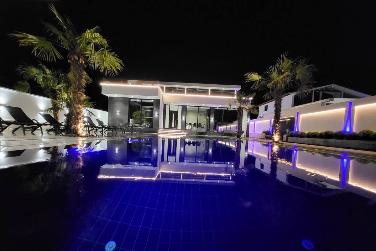 Un hôtel moderne doté d’une piscine, de chaises longues et de palmiers.