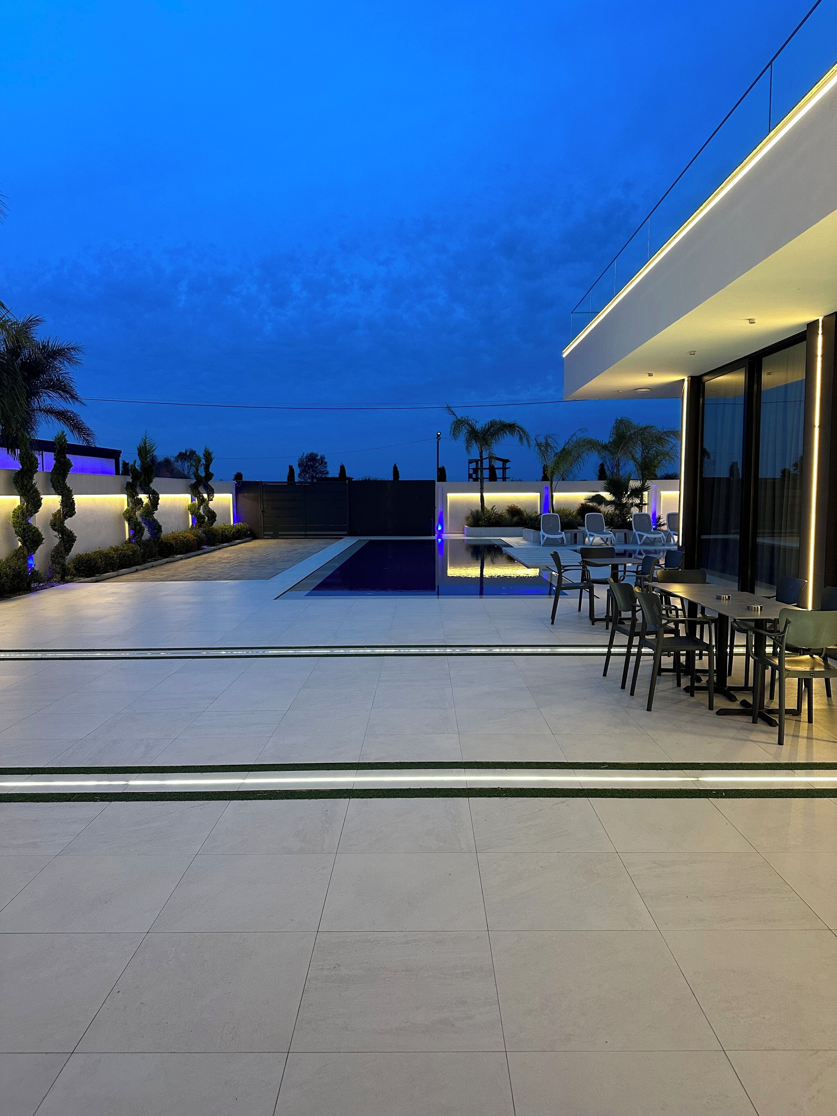 Um pátio moderno ao ar livre com piscina, área de estar e entrada bem iluminada.