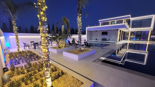 A modern villa with a pool, outdoor seating, and illuminated trees. - La Mirage Group Villas (Sukth)