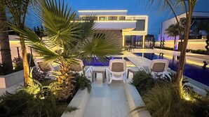 A modern outdoor pool area with lounge chairs and a pathway leading to a building. - La Mirage Group Villas (Sukth)