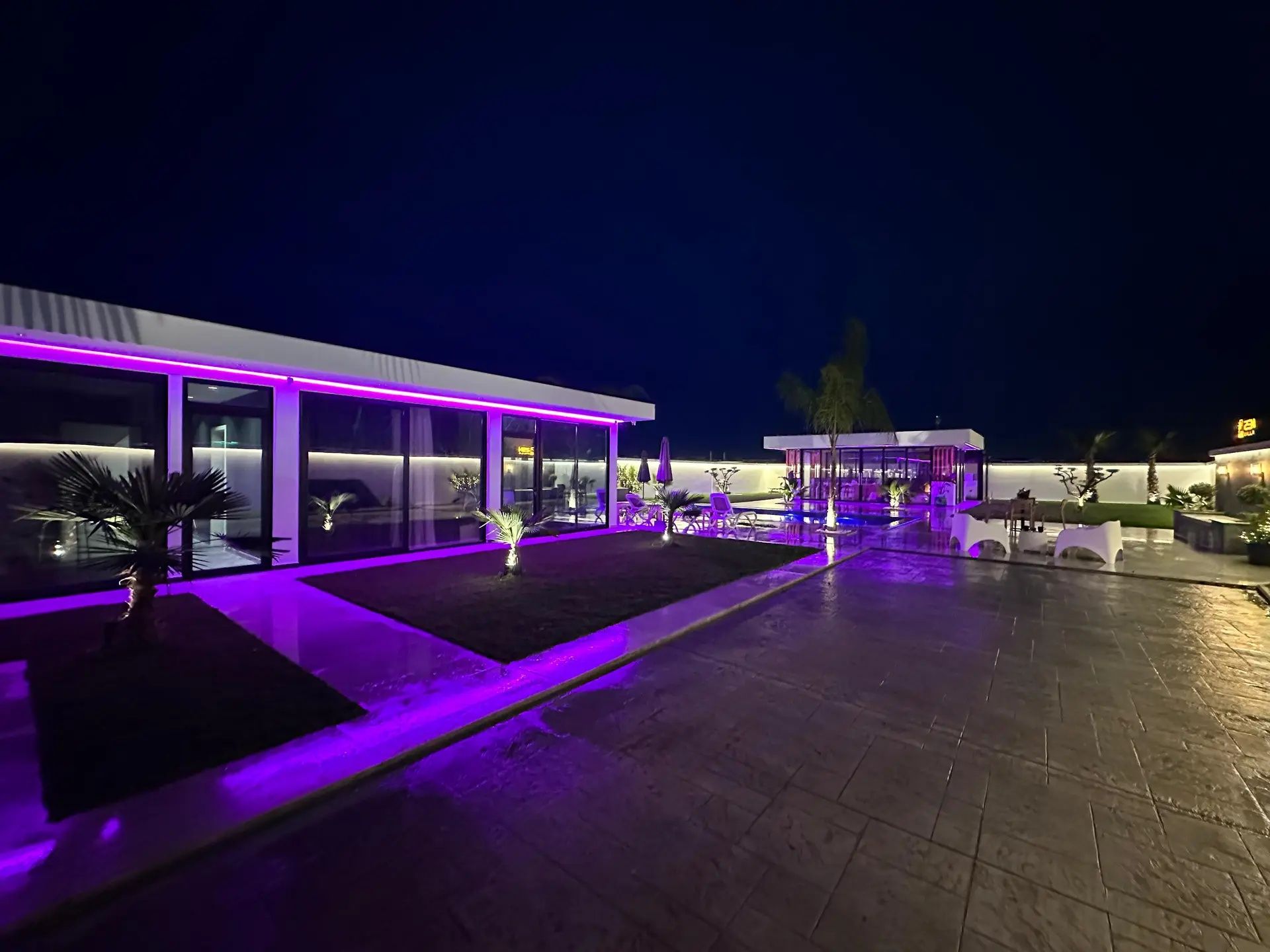 Uma área externa moderna com piscina, espreguiçadeiras e um espaço coberto para relaxar.