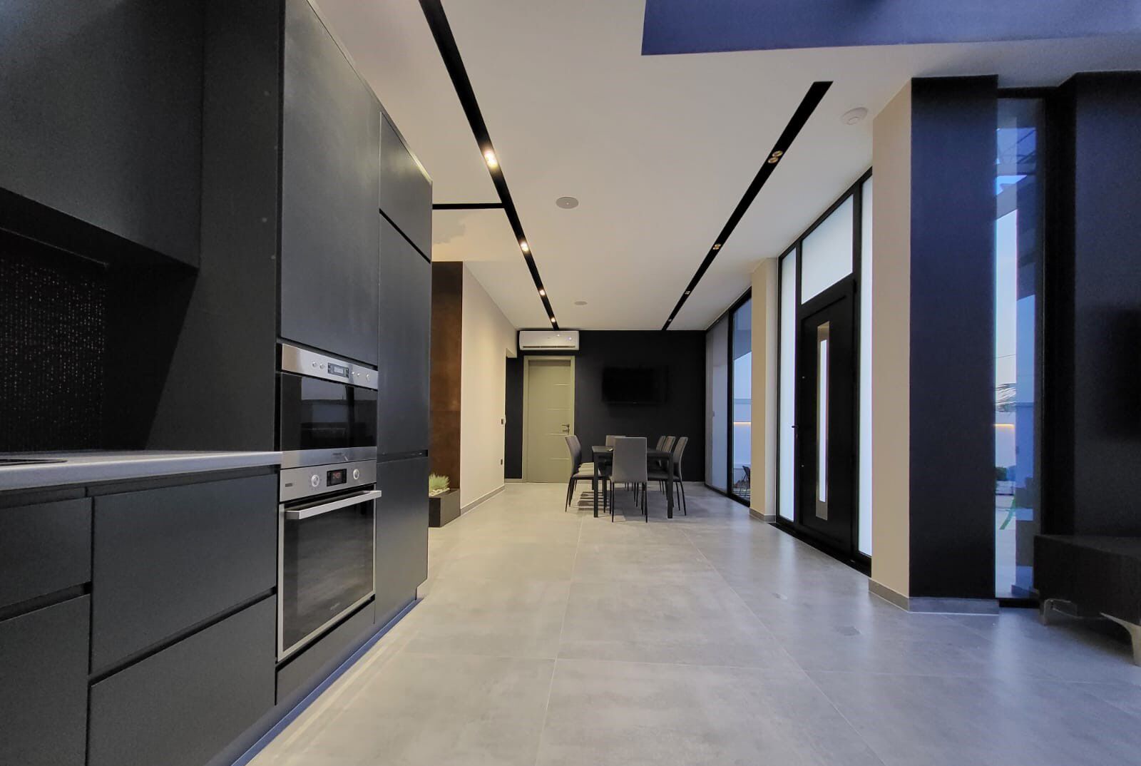 A modern kitchen with built-in appliances, a dining area with a table and chairs, and a large window providing natural light.