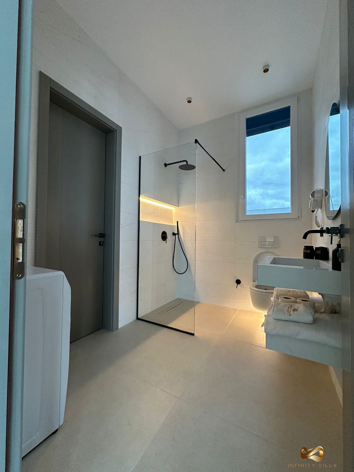 A modern bathroom with a glass shower enclosure, a white sink, and a large mirror.