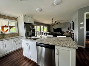 A modern kitchen with white cabinetry, a stainless steel dishwasher, and a granite countertop. - Cottage waterfront (Mallorytown)