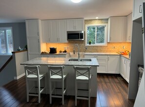 A modern kitchen with white cabinets, a granite countertop, a built-in microwave, and a large window.