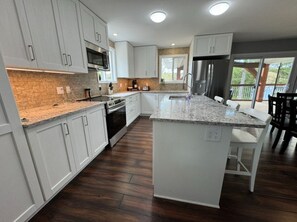 A modern kitchen with white cabinets, granite countertops, and a large island.