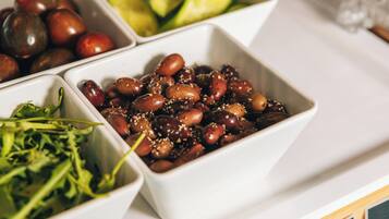 Un plateau blanc contenant divers aliments, notamment des olives, des concombres et des légumes verts.