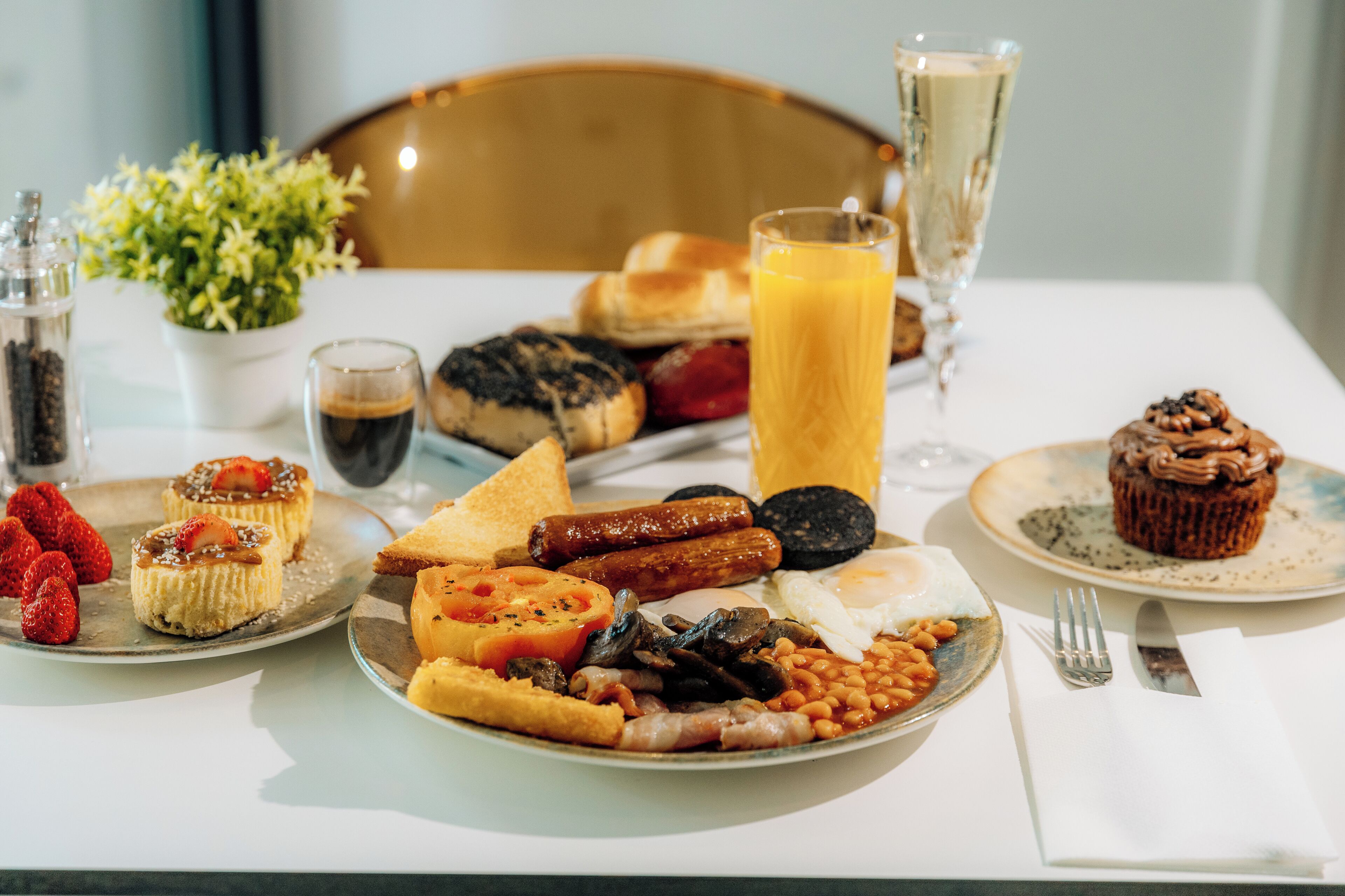 A breakfast plate with eggs, sausages, beans, toast, and a muffin.