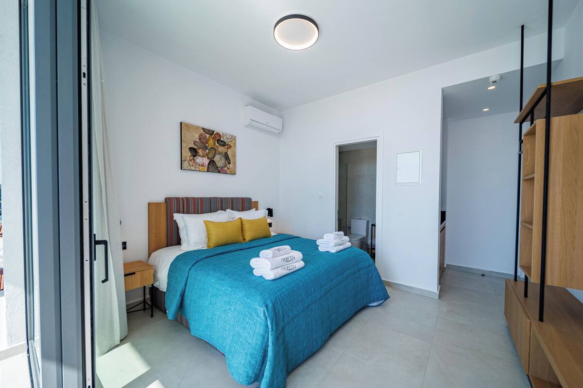Una habitación de hotel moderna con una cama grande, un cuadro en la pared y vistas al exterior.