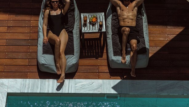 Two lounge chairs on a wooden deck with a pool below. - Regency  Boutique  Hotel (Paphos)