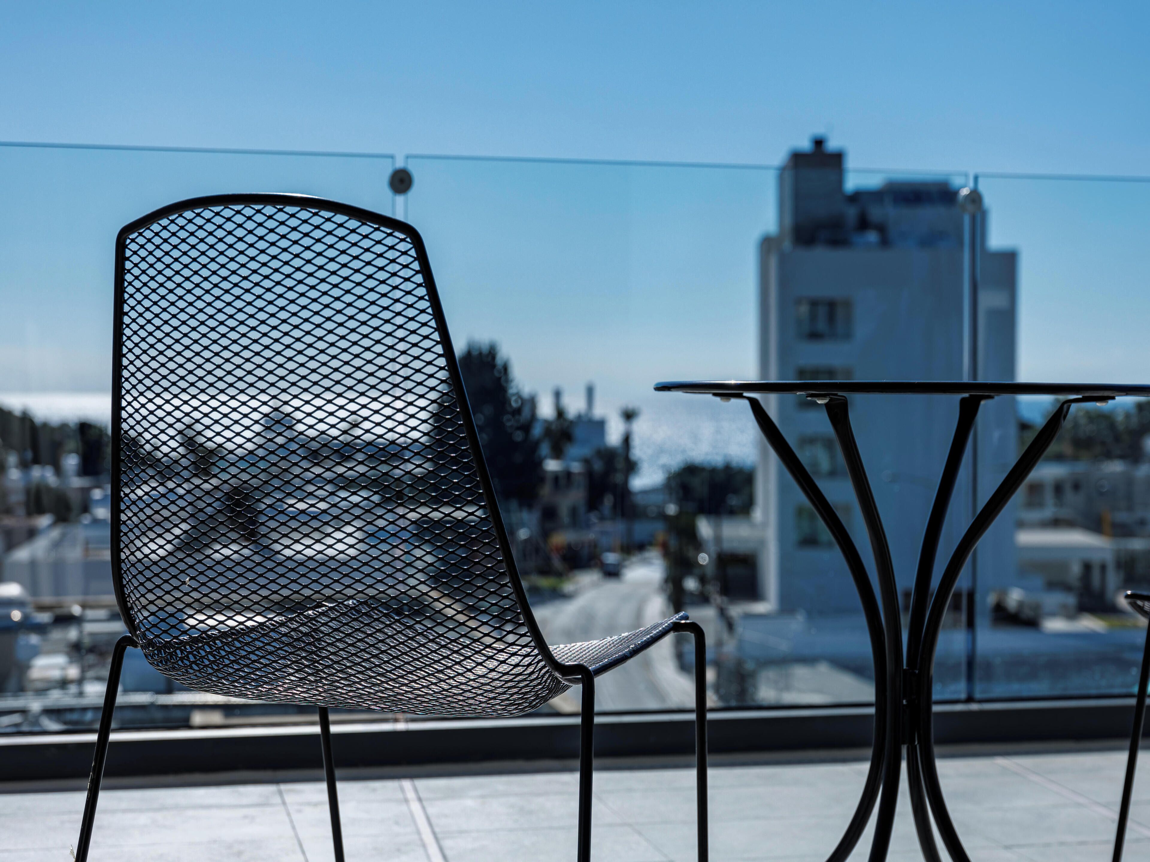 Una silla y una mesa de metal en un balcón con vista a la ciudad.