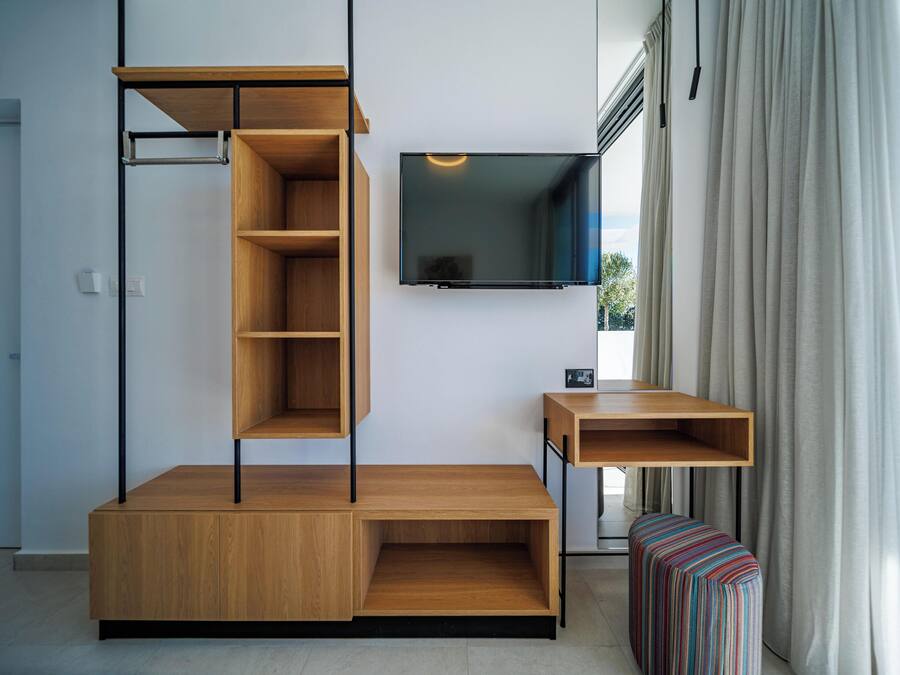 Una sala moderna con un mueble de entretenimiento de madera empotrado, un televisor de pantalla plana montado encima y una pequeña mesita de madera.