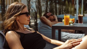 A woman reclining on a lounge chair, a man lying on a couch in the background, and a table with drinks and fruit. - Regency  Boutique  Hotel (Paphos)