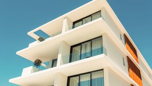 A modern multi-story building with balconies, large windows, and a clear blue sky. - Regency  Boutique  Hotel (Paphos)
