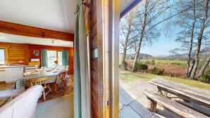 A wooden cabin with a dining area and a view of the countryside. - Balbeag Cottage - Pet friendly Log Cabin (Insh)