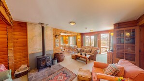 A cozy cabin interior with a stone fireplace, wooden walls, a dining area, and a sofa. - Balbeag Cottage - Pet friendly Log Cabin (Insh)