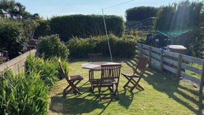A backyard with a wooden table and chairs, surrounded by a wooden fence and lush greenery.