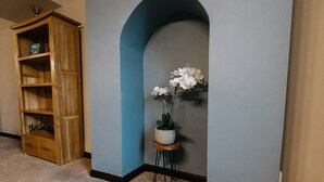 A hallway with a wooden cabinet, a small stool with a potted plant, and a blue wall. - Cumbria House: Stunning Views, 3 Bedrooms & Garden (Fletchertown)