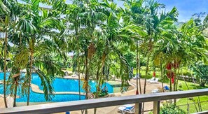 A pool surrounded by palm trees, with a view of the pool area and lounge chairs.