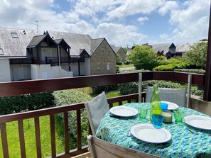 A balcony with a table set for dining, overlooking a row of houses with stone walls and pitched roofs. - REFLETS - Apartment for rent with pool, Carnac - T110 (Carnac)