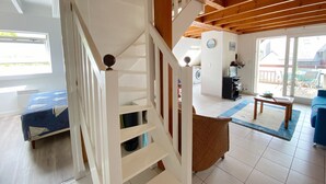 A spacious living area with a wooden staircase, a large window, and a view of the backyard.