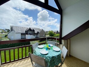 A balcony with a table set for two, overlooking a residential area with houses and a clear sky. - REFLETS - Apartment for rent with pool, Carnac - T110 (Carnac)
