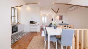 Une cuisine moderne avec des meubles blancs, un four à micro-ondes et un évier. On y trouve également un coin repas avec une table et des chaises blanches.