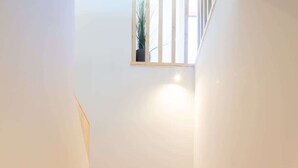 Un escalier en bois au design simple, menant à un palier doté d’une petite fenêtre.
