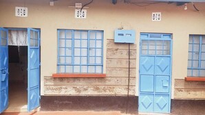 Un edificio con puertas y ventanas azules, un pequeño porche y una caja de servicios en la pared.