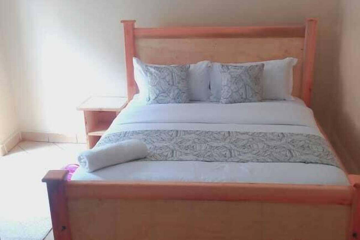 A single bed with a wooden frame and a mattress with patterned bedding.