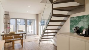 Una cocina moderna con una escalera, un área de comedor con mesa y sillas, y vistas al exterior.