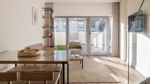Una sala de estar moderna con una mesa de vidrio, un sofá y un televisor montado en la pared.