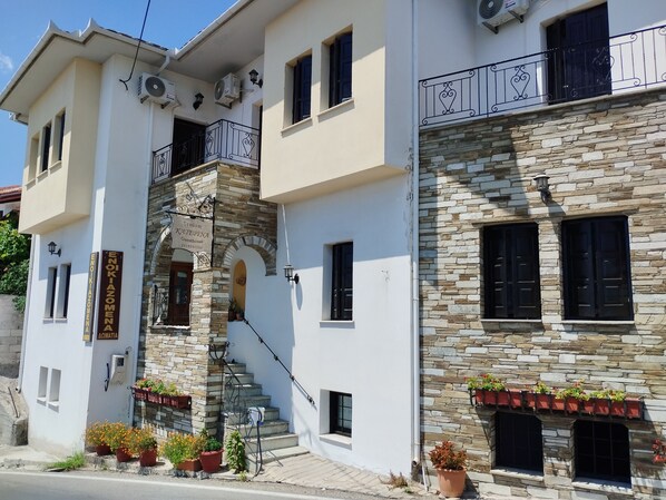 A two-story building with a stone facade, a staircase leading to the upper floor, and a sign indicating it is a guesthouse. - Catherine Portaria Guest House (Volos)