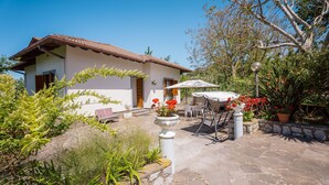 A house with a tiled roof, a patio with a table and chairs, and potted plants. - Domus Antonini (Massa Lubrense)