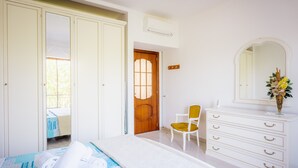 A bedroom with a bed, a dresser, a chair, and a door leading to another room. - Domus Antonini (Massa Lubrense)