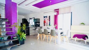 Una sala moderna con comedor, una escalera y una cocina.