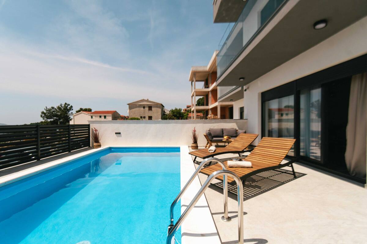 A rooftop swimming pool with lounge chairs and a modern building in the background.